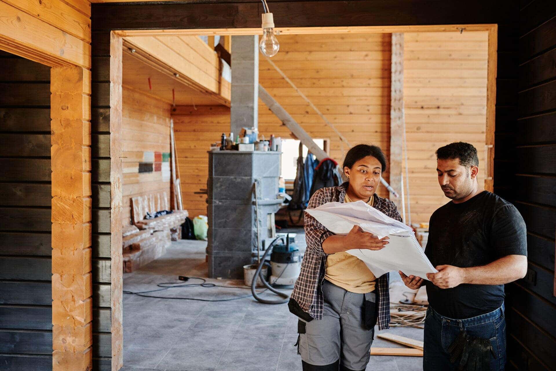 Assistante à maîtrise d'ouvrage relisant les plans dans une maison en rénovation