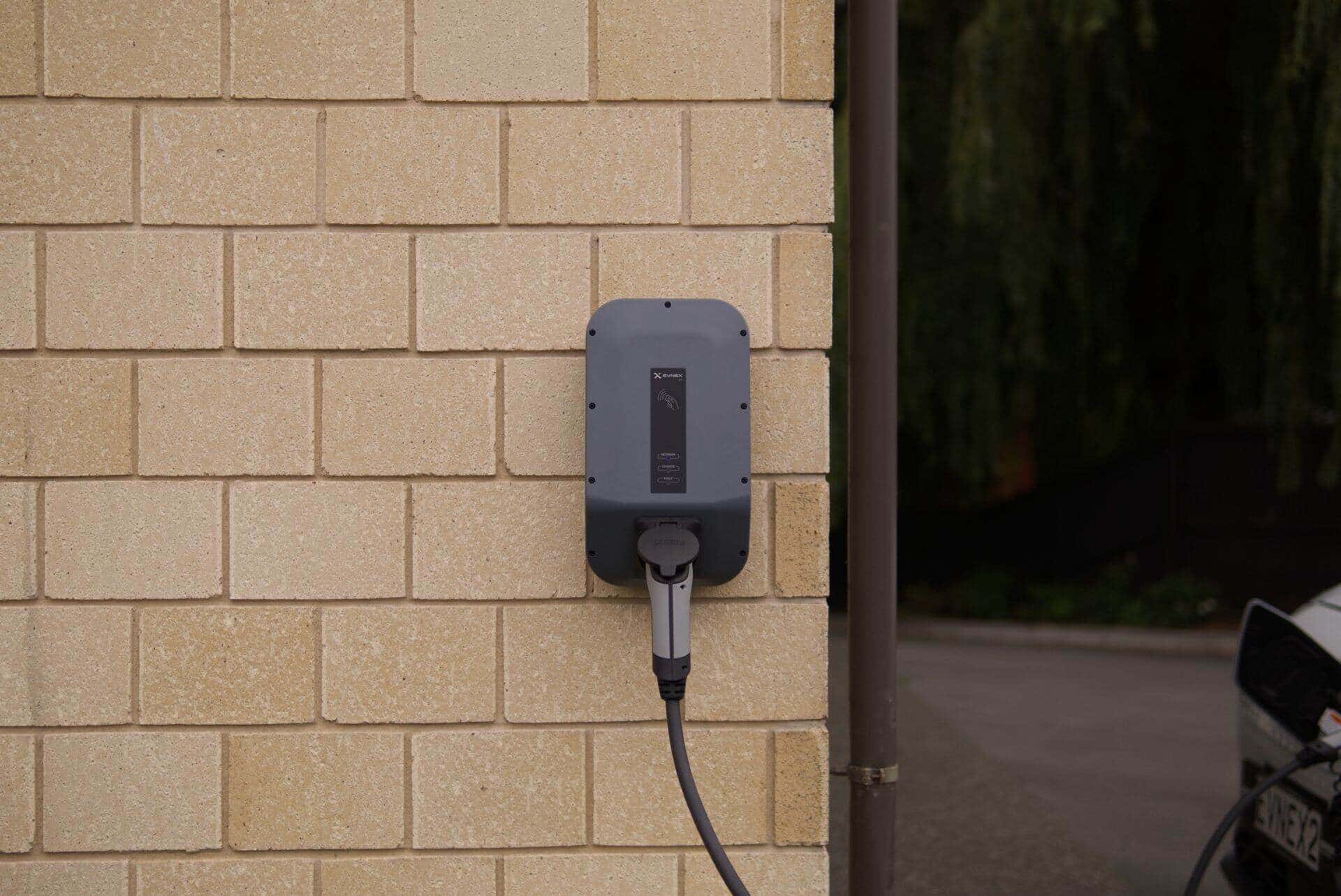 Borne de recharge pour véhicule électrique posée sur un mur de brique