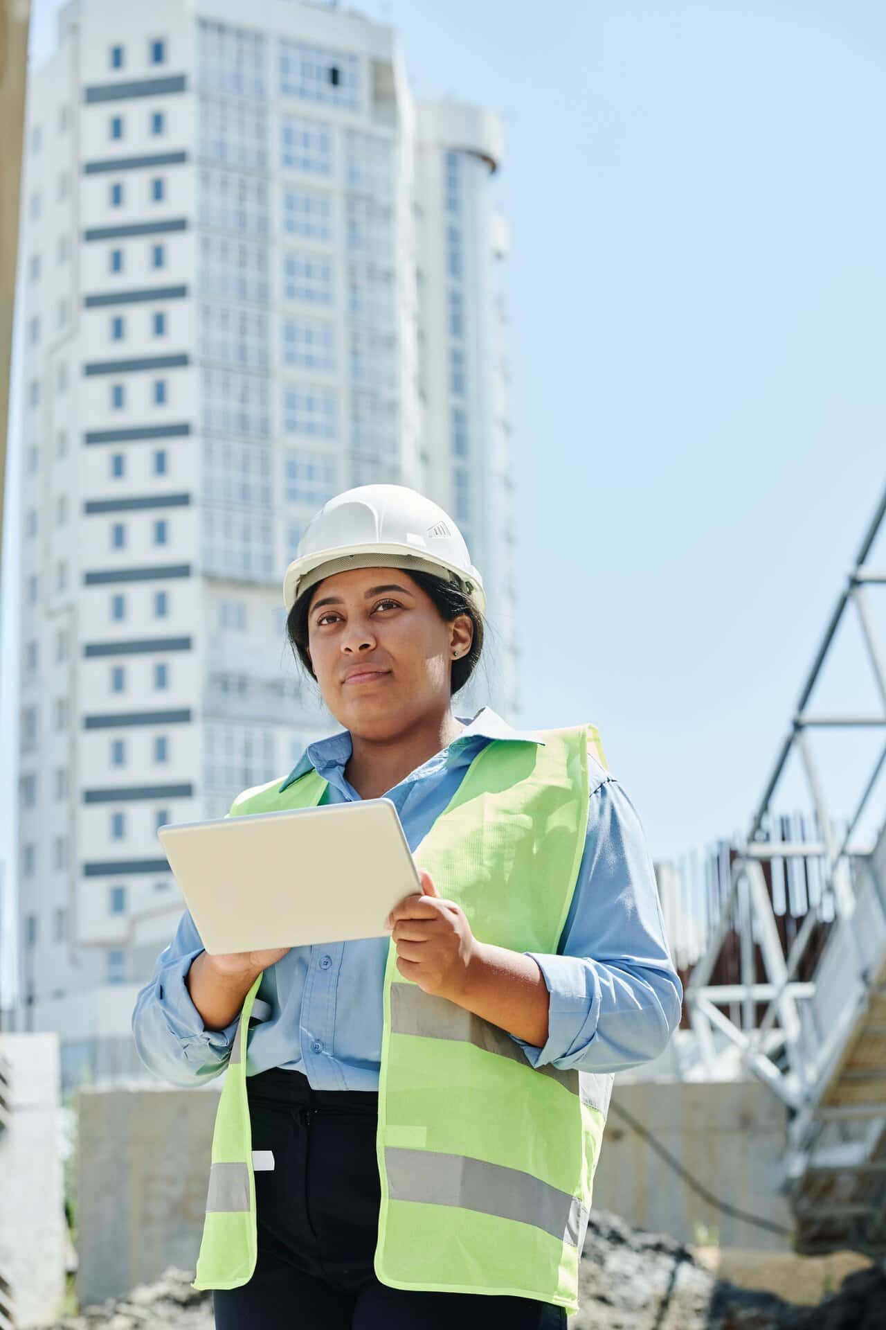 Conductrice de travaux casquée, tablette en main, sur un grand chantier