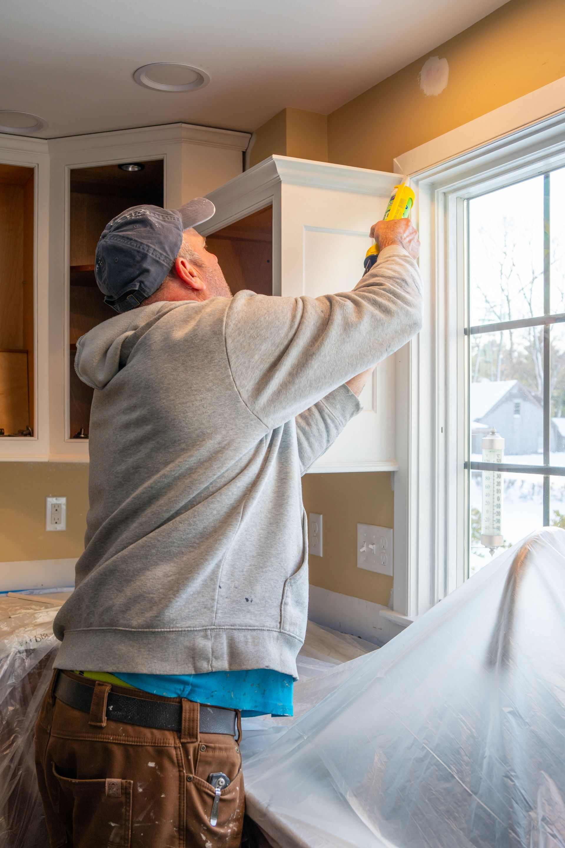 Cuisiniste finalisant la pose d'un meuble de cuisine sur mesure, chantier de rénovation