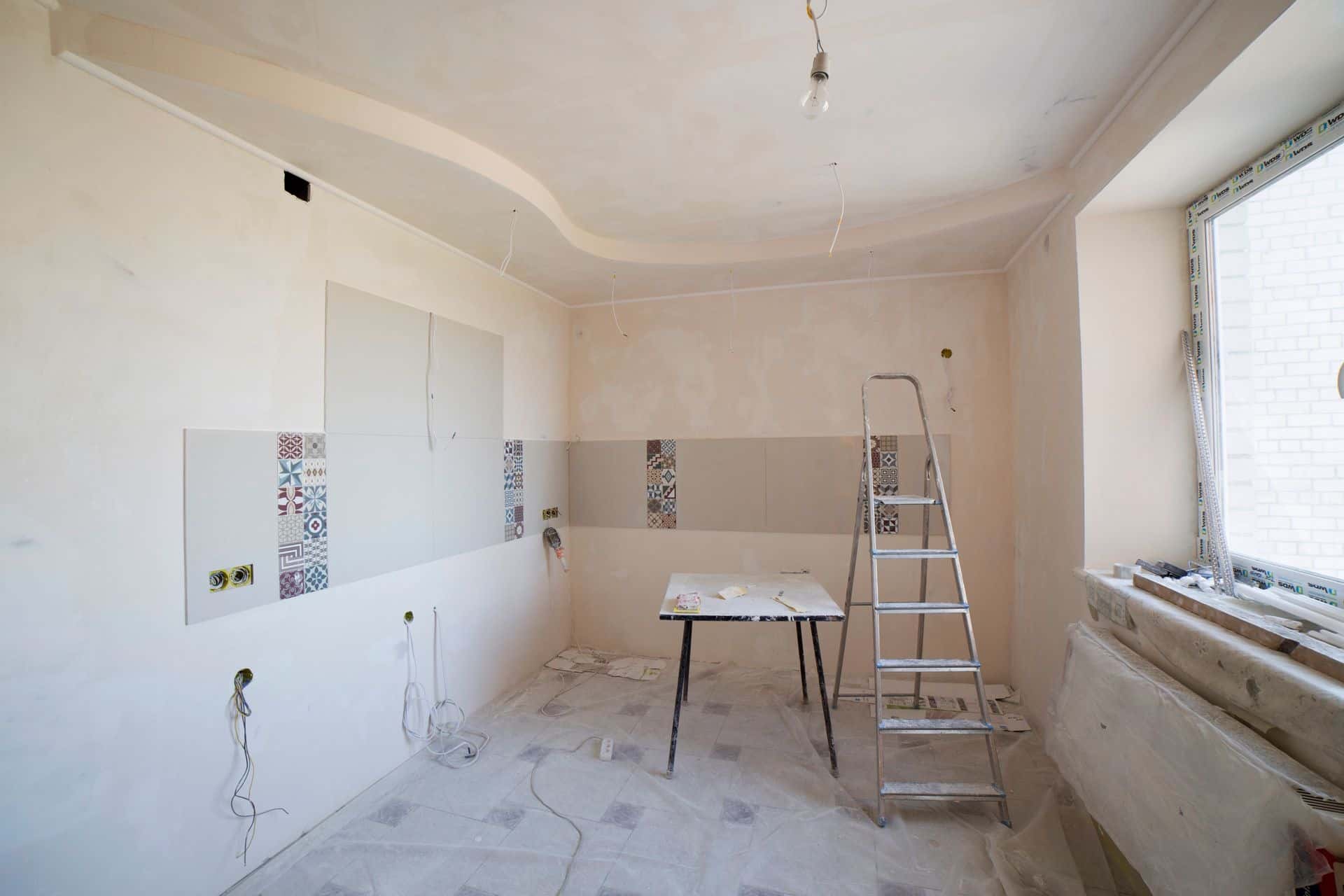 Pièce d'un appartement vidé pendant sa rénovation, escabeau et murs enduits