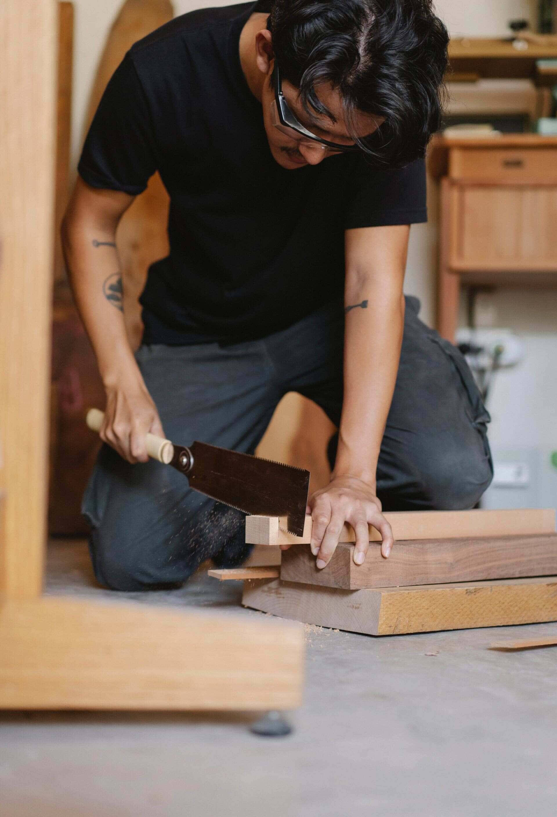 Menuisier sciant une pièce de bois sur son établi