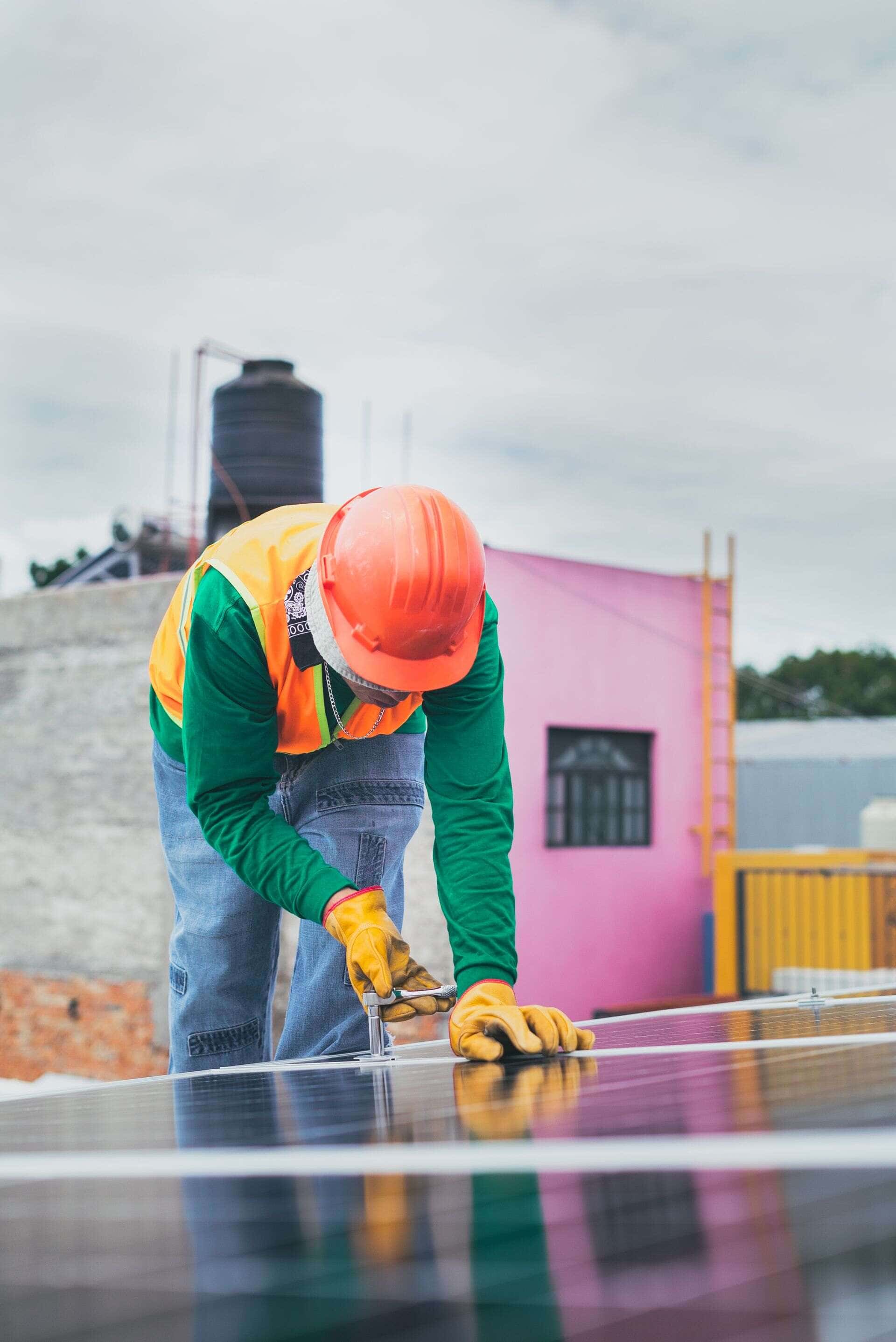 Installateur casqué manipulant un panneau photovoltaïque sur un toit